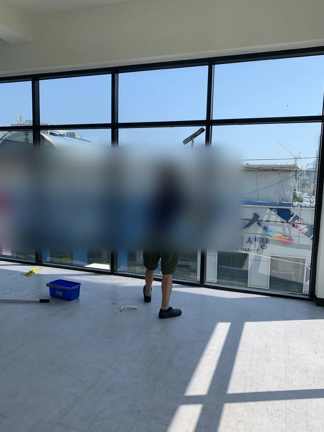 긴 폴대 도구로 대형 유리면의 상부를 밀어 올리며 작업하는 장면